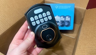 hand holding a keyless entry keypad fingerprint door lock