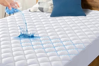 Lifestyle image of a Hoey Mattress Protector: close up of liquid being poured on it to demonstrate it's waterproof 