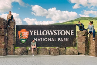a family posing on the Yellowstone National Park sign