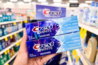 hand holding two crest toothpastes