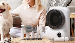 a woman and dog next to a grooming vacuum/dryer