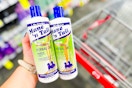 person holding 2 bottles of mane n tail shampoo over a cart