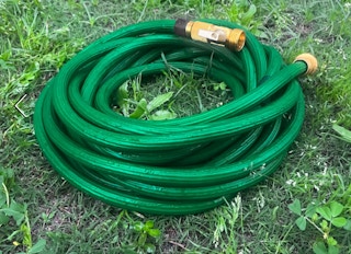 a green garden hose in grass