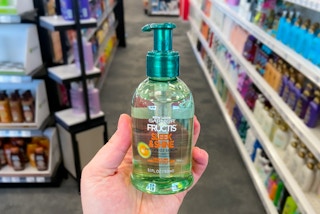 hand holding garnier fructis sleek and shine anti frizz serum in a grocery aisle