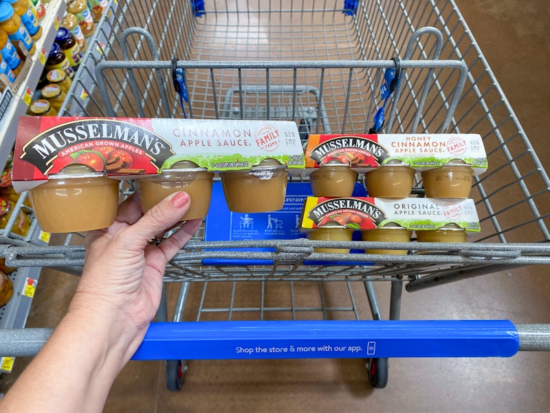 hand holding musselmans applesauce over walmart cart