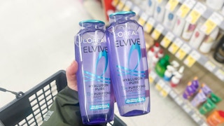 person holding loreal elvive shampoo bottles