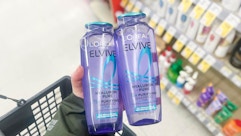 person holding loreal elvive shampoo bottles