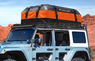 a jeep with a large orange and black cargo carrier on the roof of the car