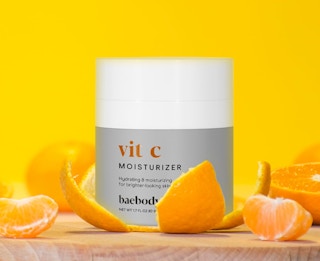 a face cream jar sitting in orange peels next to orange slices