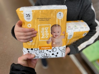 two people exchanging a pack of hello bello diapers