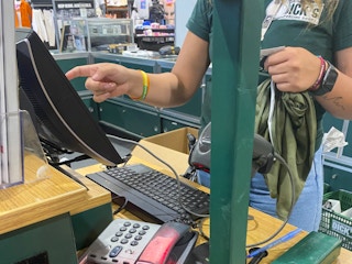 A Dick's Sporting Goods employee at the register ringing up an item.
