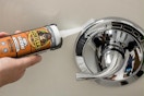 person apply silicone sealant to shower handle