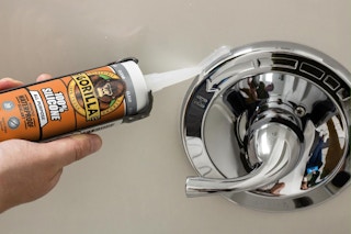 person apply silicone sealant to shower handle