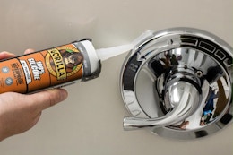 person apply silicone sealant to shower handle
