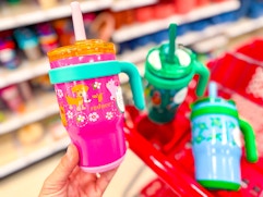 hand holding a reduce tumbler in front of a target cart