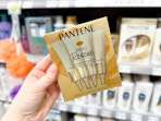 hand holding a box of pantene-miracle-rescue in walmart aisle