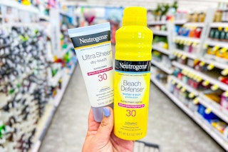 hand holding two bottles of sunscreen in store aisle