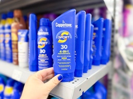 hand grabbing a Coppertone Suncreen bottle