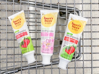 A variety of Burt's bees kids toothpaste sitting in a store cart.