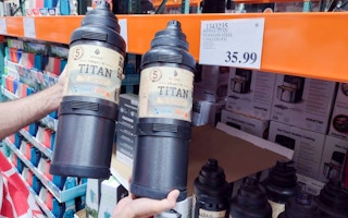 one gallon jug hand held near sales tag at costco