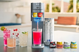 Lifestyle image of the Ninja Thirsti machine on kitchen counter with drink mixes and drinks made
