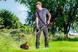 Lifestyle image of the TNTANTS Electric Weed Wacker being used outdoors to trim down long grass/weeds