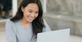person smiling and working on laptop