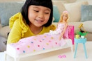 child playing with a Barbie doll and the bedroom playset accessories