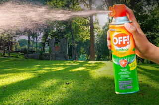 person spraying insect repellent into their yard