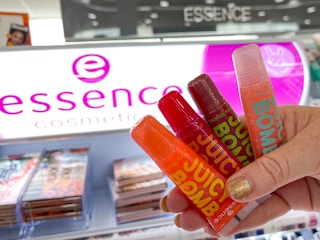 hand holding essence lip gloss in front of display