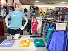 Nike apparel sitting on a table alongside nike apparel hanging on a store rack.