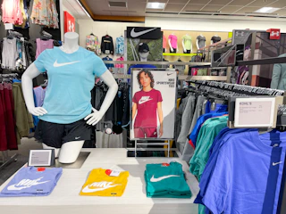Nike apparel sitting on a table alongside nike apparel hanging on a store rack.