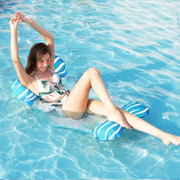 a person laying in a pool on a pool hammock
