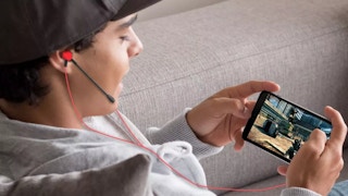 a boy with earbuds playing a game on his phone