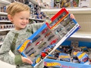 A little boy smiling and holding a large pack of Hot Wheels cars in an aisle at Target.