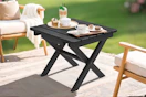 Lifestyle image of a black patio folding table set up outdoors