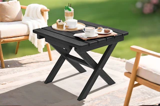 Lifestyle image of a black patio folding table set up outdoors