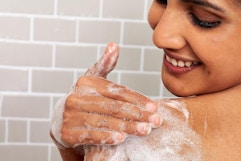 Aveeno Body Wash woman lathers her shoulder and smiles