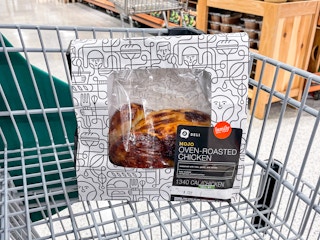 A packaged mojo rotisserie chicken sitting in a shopping cart inside Publix.