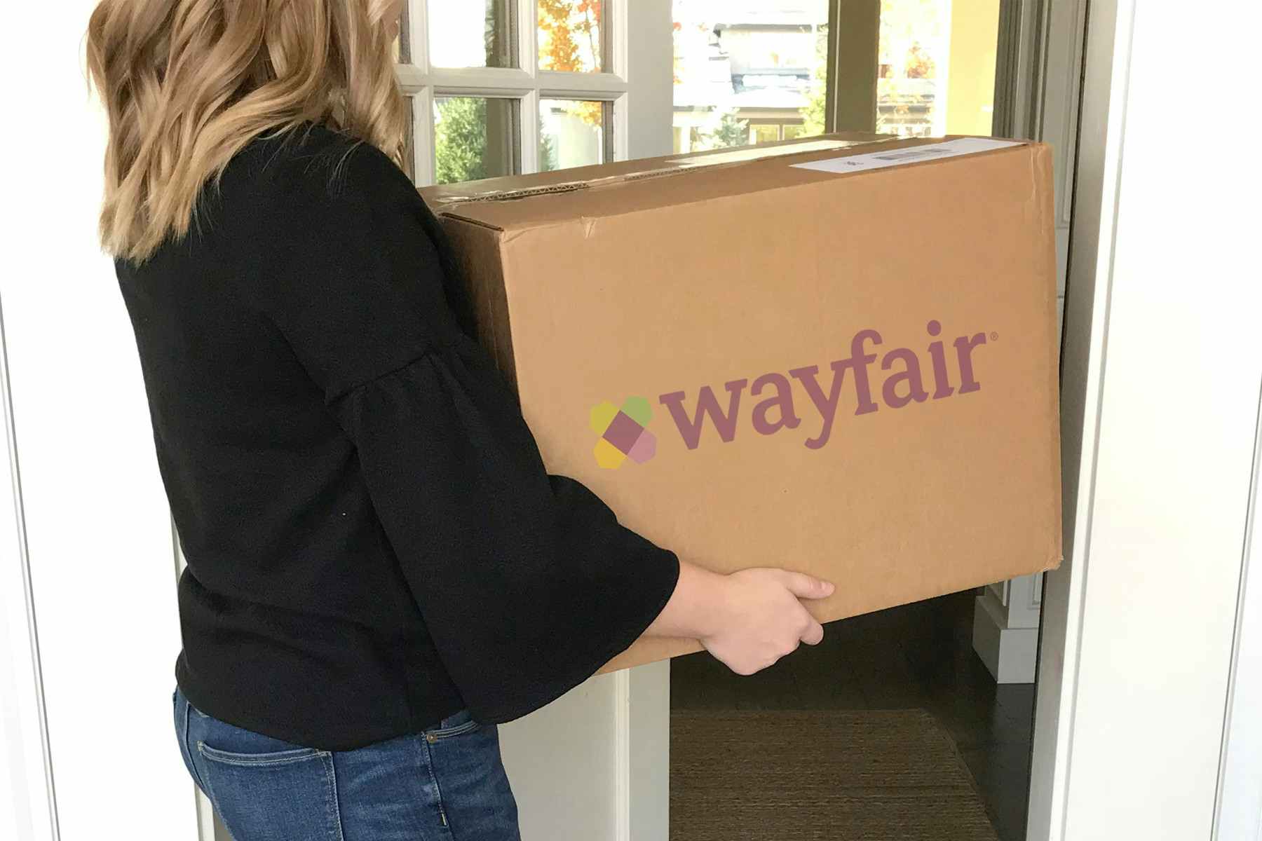 woman brings wayfair box into her home
