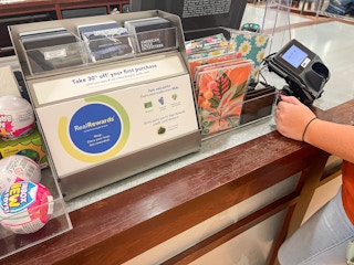 A person buying some items next to a sign for Real Rewards at the counter in an American Eagle store