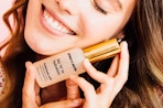 a woman holding a bottle of face serum against her face