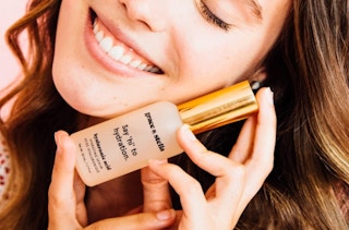 a woman holding a bottle of face serum against her face