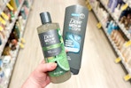 hand holding two Dove Men+Care body washes in a store aisle