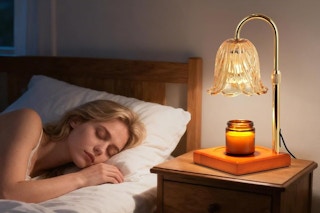 a woman sleeping next to a candle warmer lamp