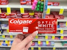 hand holding box of Colgate Optic White Stain Fighter toothpaste
