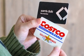 someone holding up sams club and costco membership cards