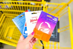 hand holding domino's, wendy's, taco bell gift cards