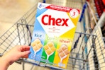 hand holding a box of chex cereal over shopping cart