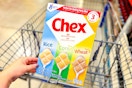 hand holding a box of chex cereal over shopping cart
